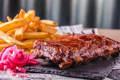 Close up view of grilled BBQ ribs with french fries served and ready to eat Stock Photos