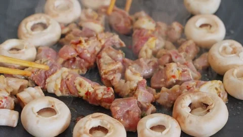 Close up view of grilled marinated lamb cubes and white mushrooms on a sizzling Stock Footage 341649354