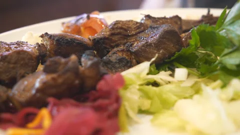 A close up view of grilled meat pieces with vegetables. Stock Footage 136415496