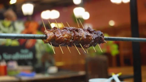 A close-up view of grilled meat on a spit at a Thai night market Stock Footage 329598741