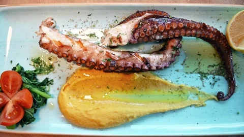 A close up view of grilled octopus served with hummus, cherry tomatoes, and.. 库存影片 339202704