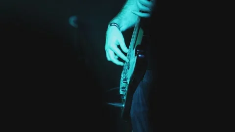 Close-up view of a guitarist’s hand on strings under variable colored lights in 스톡 동영상 308366832