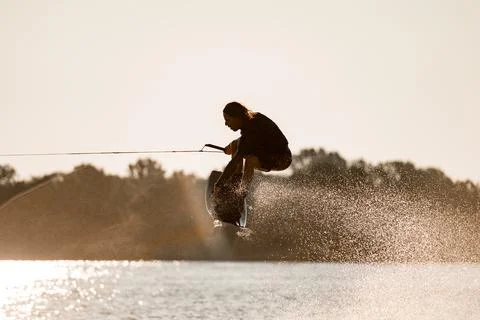 Close-up view of guy holding rope and skillfully jumping high with wakeboard 스톡 사진