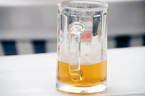 Close-up view of a half-empty glass beer mug sitting on a table surface Stock Photos