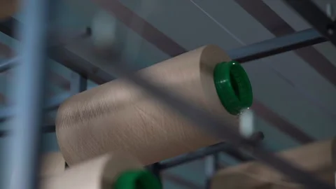 Close view of hand adjusting large beige thread spool on textile machine rack Stock Footage 321888325