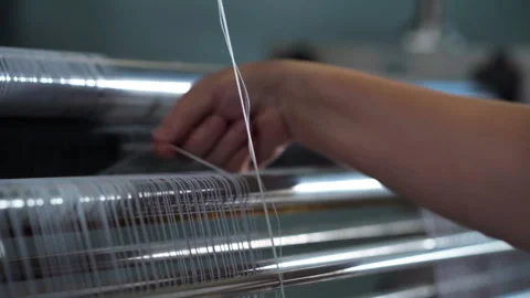Close view of hand adjusting white textile threads polished metal weaving rolles Stock Footage 321888108