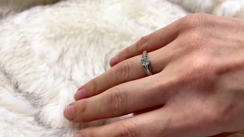 Close-up view of a hand adorned with a diamond ring placed on soft white fur Stock Footage 329913779