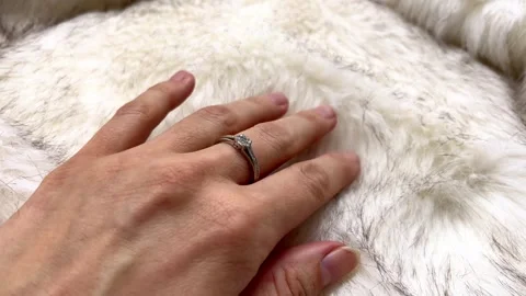Close-up view of a hand adorned with a diamond ring placed on soft white fur Stock Footage 336311438