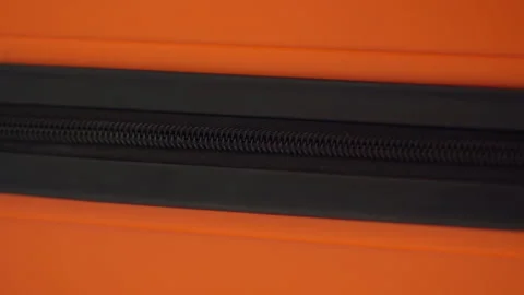 Close view of hand closing zipper on bright orange travel suitcase Stock Footage 321708414