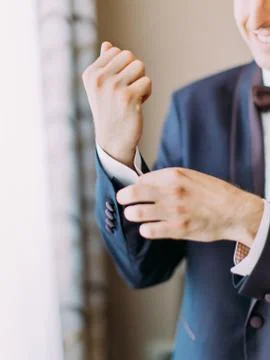 Close-up view of the hand of the groom buttoning the wedding jacket. Stock Photos