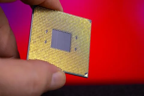 Close view of a hand holding a computer microprocessor with a shiny gold surface 스톡 사진
