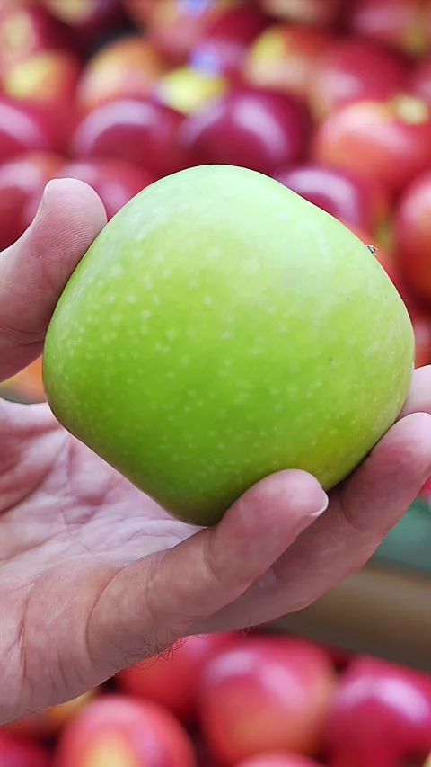 Close-up view of a hand holding a green ripe apple in a grocery store Stock Footage 336663557