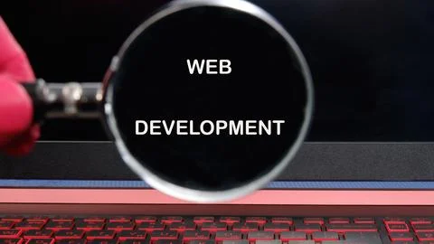 A close-up view of a hand holding a magnifying glass over the text web deve.. Stockfoto's