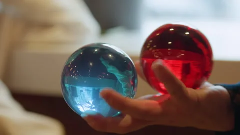 Close up view of hand holding two colorful glass spheres one red and one blue in Stock Footage 344872804