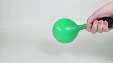 A close up view of a hand inflating a green balloon with a pink pump on a w.. Stock-Footage 333808631