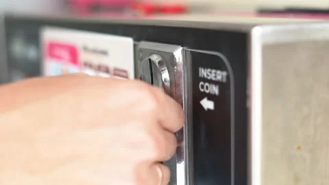 Close-up view of a hand inserting a coin into a machine Stock Footage 234865423