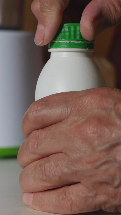 A Close-Up View Of A Hand Opening A Bottle Cap, Lifting The Bottle Off The Table Stock Footage 312981355