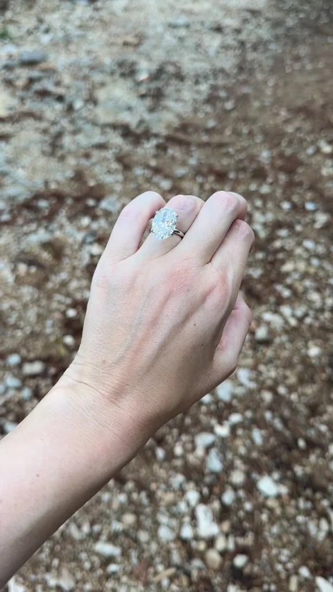 Close view of hand with oval diamond engagement ring on rocky path Stock Footage 319455922