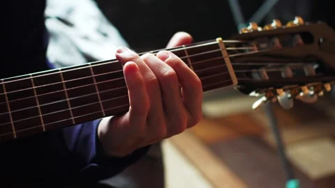 Close view of a hand playing guitar strings in a cozy room during a music practi Stock Footage 330889574