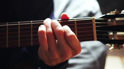 Close view of a hand playing guitar strings in a cozy room during a music practi Stock Footage 333646146