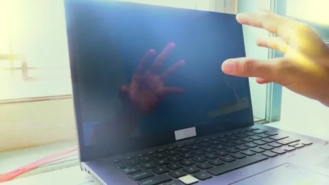 A close up view of a hand reaching out to touch a black laptop screen refle.. Vídeos de archivo 345139134