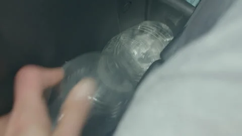 Close view of hand reaching for plastic bottle in car interior Stock Footage 325073228