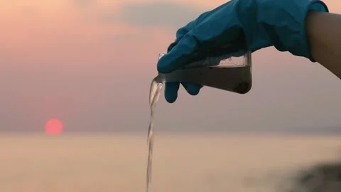 Close up view of hand in rubber glove testing sample flask of dirty water Video stock 257399040