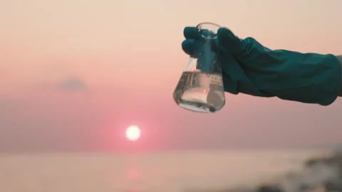 Close up view of hand in rubber glove testing sample flask of pure water Stock Footage 260603347