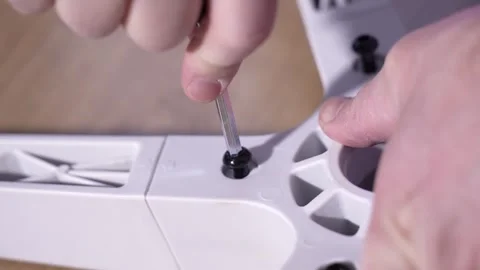 Close-up view of a hand tightening a bolt with a hex key while assembling an Stock Footage 327910017