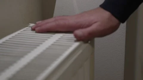 Close view of a hand touching the top grille of a household radiator to check Stock-Footage 324521530