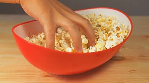Close-up view of hand that tries to grab as many popcorn from the bowl as pos Video stock 65113976