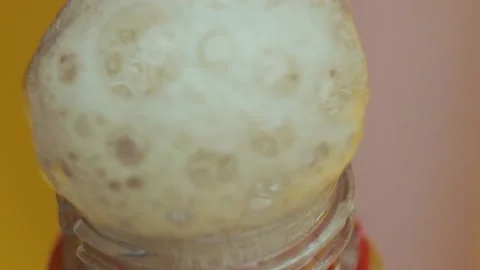 Close up view of hand unscrewing the cap from a soda bottle. Slow motion, splash Stock Footage 147673399