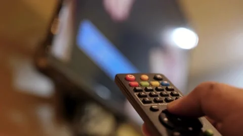 Close up view of a hand using television remote control at home. Changing c.. Stock Footage 257874919