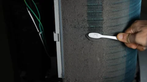 Close view of a hand using a toothbrush to clean dust from a dirty air cond.. Stock Footage 338319344
