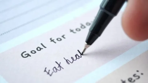 Close up view of hand writing eat healthy food as goal for today in planner.. Stock Footage 333031535