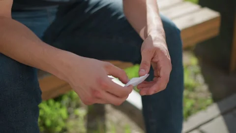Close view of hands applying nicotine patch outdoors in sunlight 스톡 동영상 307054937