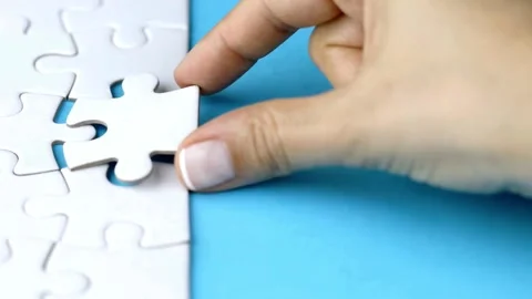 Close up view of hands assembling jigsaw puzzle on table, group of business Stock-Footage 336248632