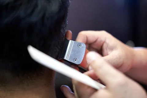 Close up view of the hands of a barber cutting hair with a hair clipper Stock Photos