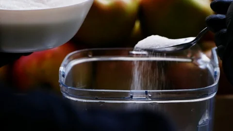 Close up view of hands in black gloves pouring, adding sugar into the bowl Stock-Footage 99312423