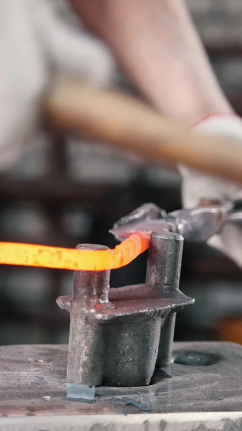 Close up view - hands of Blacksmith with gloves in forge makes steel knife Stock Footage 332614496