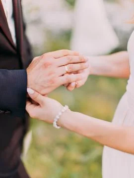 Close-up view of the hands of the bride putting the wedding ring on the finger Stock Photos