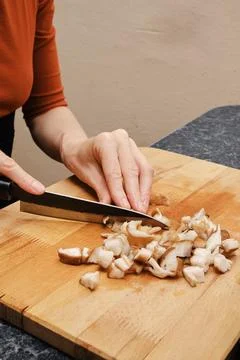 Close up view of hands cutting shiitake on wooden cutting board Stock Photos