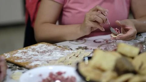 Close view of hands folding dumpling dough with minced meat filling on a flour Stock Photos