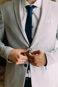Close-up view of the hands of the groom buttoning the jacket. Stock Photos