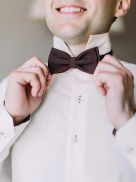 Close-up view of the hands of the groom correcting the bow-tie. Stock Photos