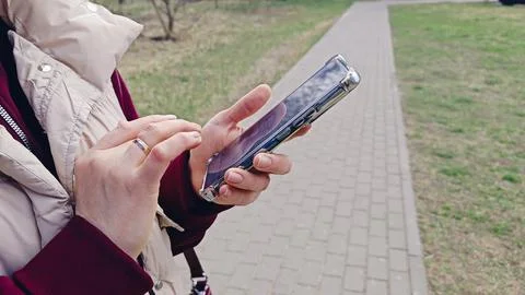 Close Up View of Hands Holding Cell Phone while Standing Outdoors. 스톡 사진