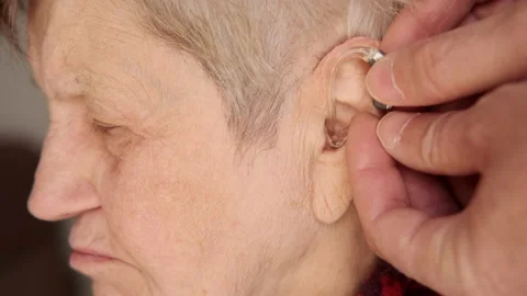 Close-up view of hands inserts hearing aid device to the elderly woman's ear Stock-Footage 168835981