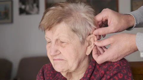 Close-up view of hands inserts hearing aid device to the elderly woman's ear Stock-Footage 168839283