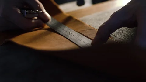 Close-up view of hands of a leather cutting leather sheet to make leather Stock Footage 71388899