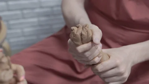 A close-up view of the hands of a man and woman sculpting clay. Stock Footage 128577713